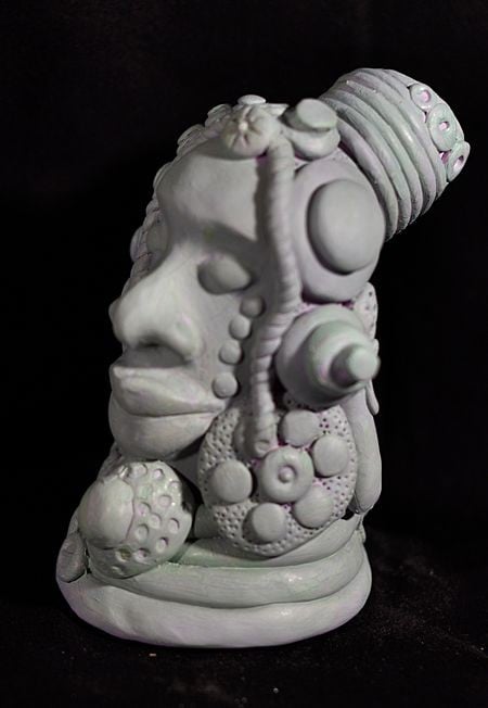 
Head of man with ornate headdress, a whimsical rendition of man across cultures in grey polymer clay by artist, Hollis Richardson   
