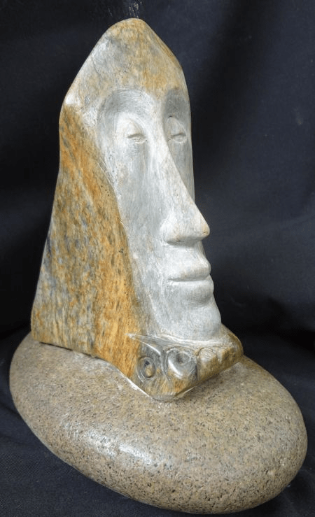 Soapstone carvied sculpture of man;selongated face on rock by artist Hollis Richardson